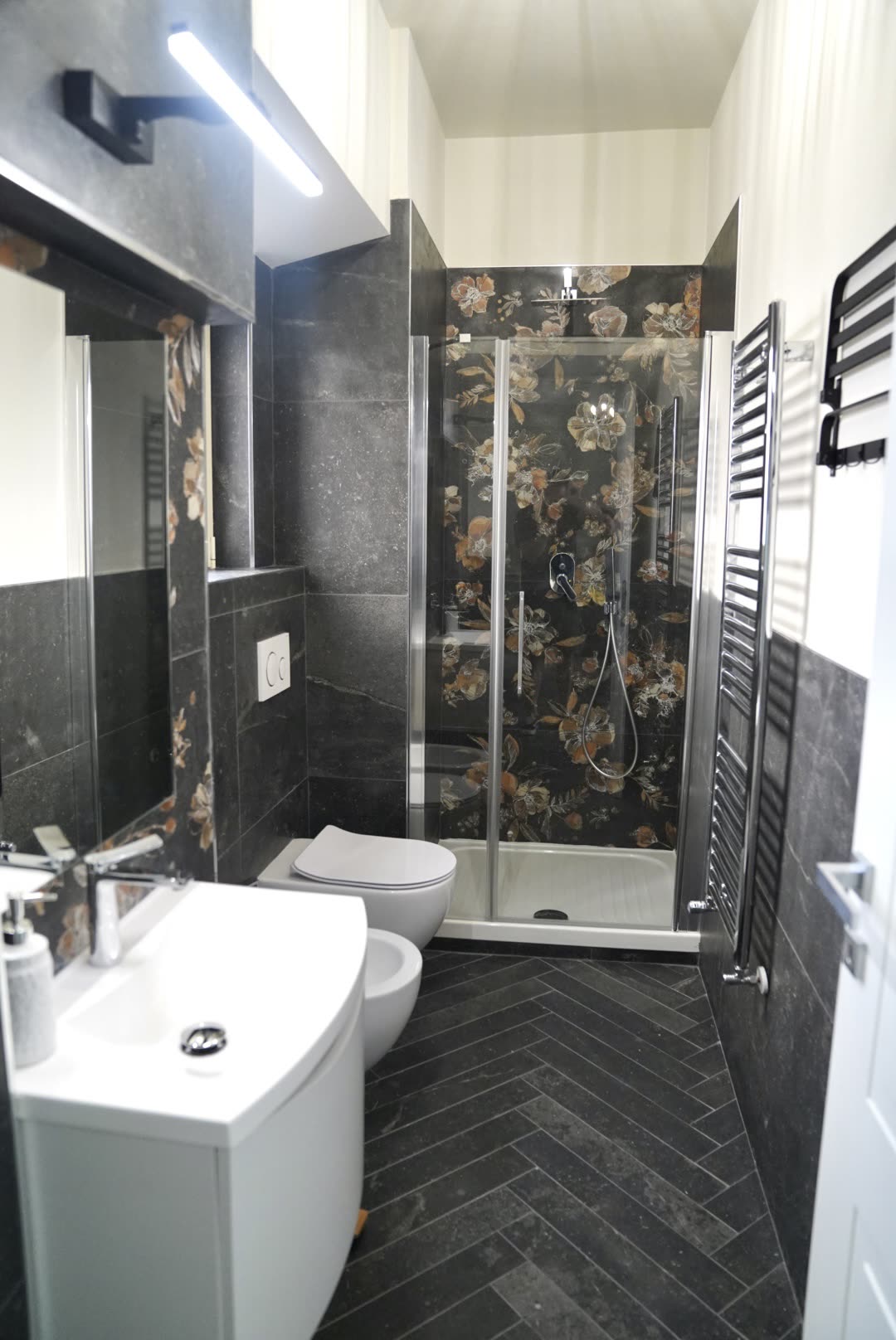 Walk-in shower with patterned floral tiles and glass screen in the apartment bathroom