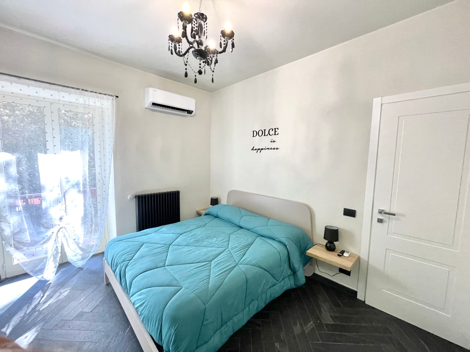 Bedroom at Dolce Apartments with a double bed, turquoise linen, air conditioning and balcony door in Castel Gandolfo